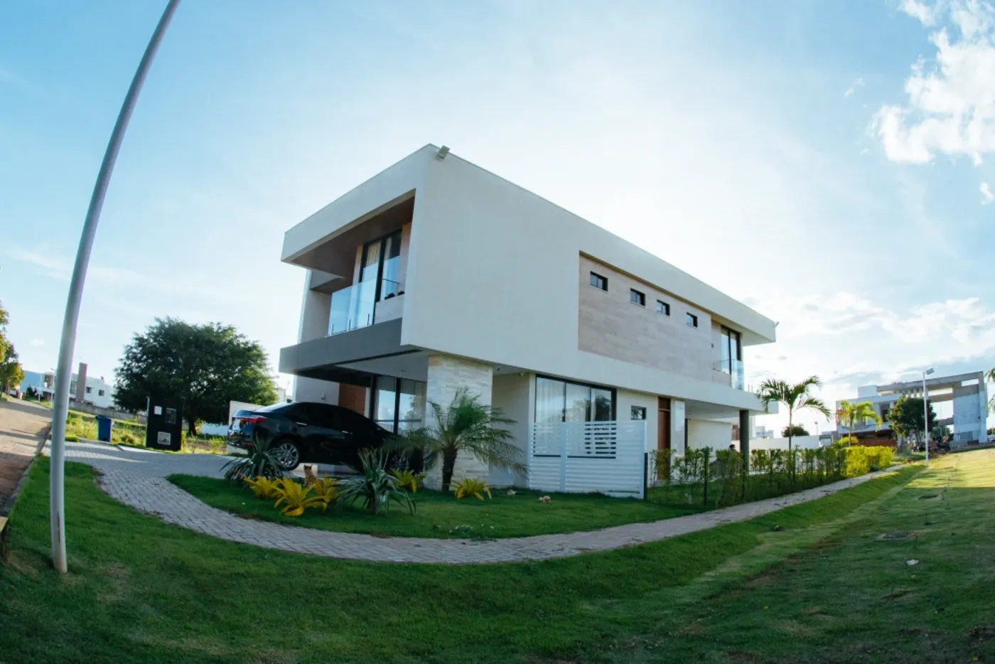 Residência de alto padrão em dois pavimentos, com volumes brancos em balanço e revestimento em pedra