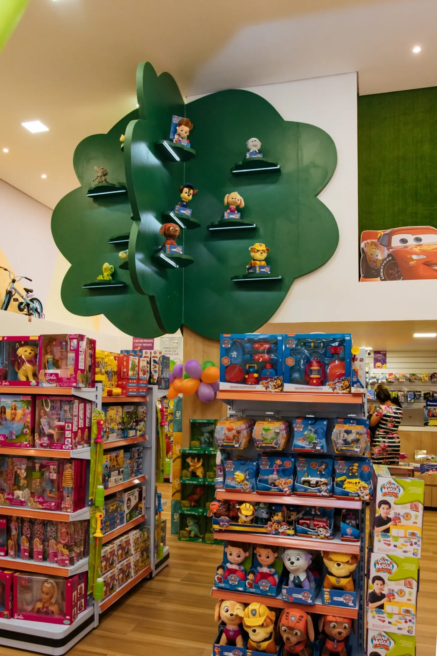 Loja de brinquedos com painel decorativo em forma de copa de árvore e gôndolas iluminadas